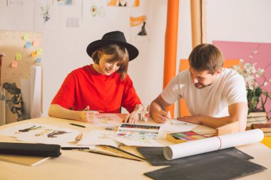 Genç kız ve erkek sanatçı tasarımcılar stüdyoda çizgi film yaparlar. Sanat okulu veya sanat blogu ilanı için fotoğraf