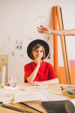 Şapkalı genç ve güzel bir sanatçı stüdyoya gelir. İç görü, elinde bir ampul ile sembolize edilir.