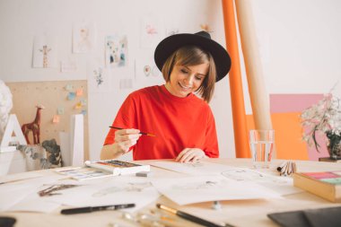 Şapkalı genç kız, stüdyoda suluboya resim çiziyor. Reklam kursları, illüstrasyonlar veya blog için fotoğraf
