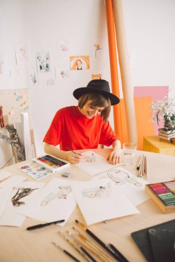 Şapka çizerindeki yaratıcı gülümseyen kız bir film ya da çizgi film için çizim tahtası çiziyor.