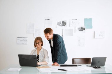 Genç yaratıcı tasarımcı takımı gülümseyen kız ve erkek dizüstü bilgisayardaki projeyi geliştiriyor. Tasarım hizmetleri