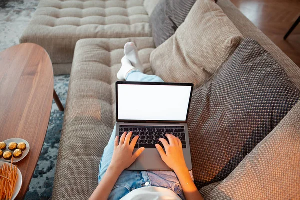 Tini lány fekszik a kanapén üres képernyős laptop néz sorozat hangulatos légkörben. Közelkép fotózás reklám vagy blog — Stock Fotó
