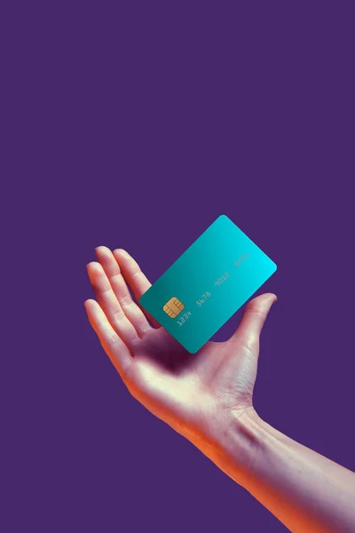 Primer plano mano femenina sostiene plantilla levitante maqueta tarjeta de crédito del banco con servicio en línea aislado sobre fondo violeta —  Fotos de Stock