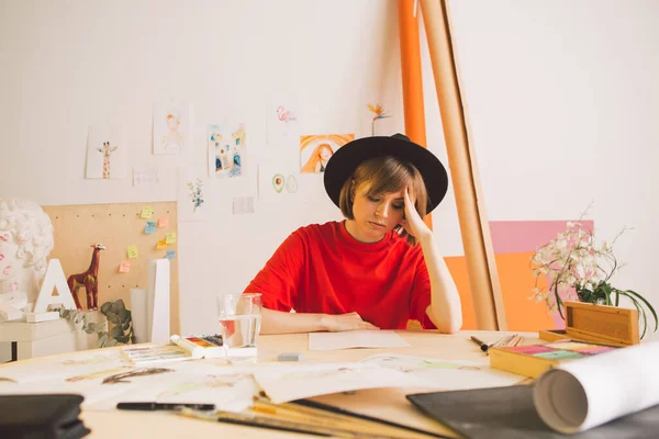 Tråkig flicka Illustratör konstnär knäppt huvud sitter vid bordet i studio. Tillstånd av apati, frustration och kreativ kris — Stockfoto