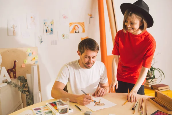 Kreatív fiatal lány művész blogger tanít akvarell festészet műhelyben. A fickó megtanul akvarellt rajzolni.. — Stock Fotó