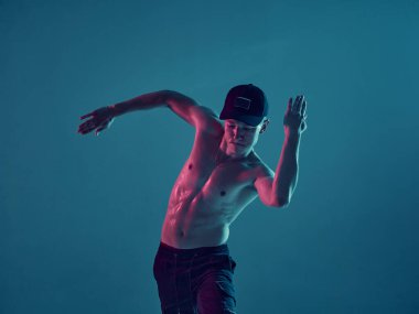 Neon ışıklı stüdyoda tişörtsüz dans eden çocuk. Akrobatik dansçı. Biçimlendirme.