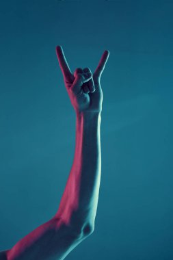 Erkek el, keçi jesti. Mavi ışık arka planında izole edilmiş. Konsept fotoğrafçılık, müzik afişi, rock 'n roll
