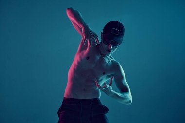 Neon ışıklı stüdyoda tişörtsüz dans eden çocuk. Akrobatik dansçı. Biçimlendirme.