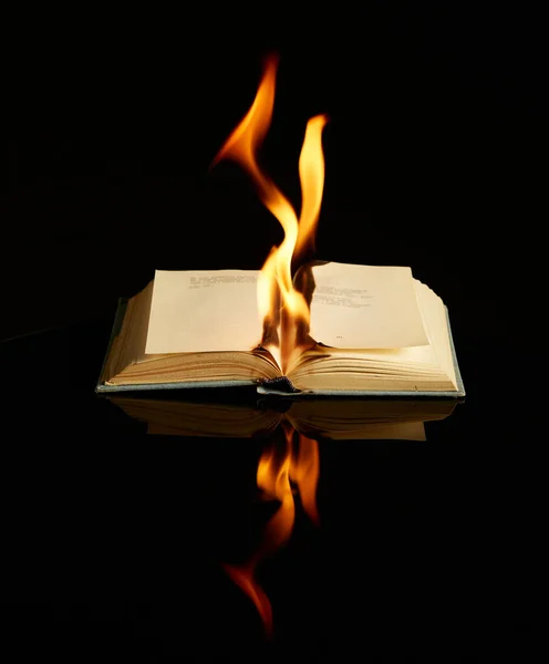 Burning βιβλίο απομονώνονται σε μαύρο φόντο και ανακλαστική επιφάνεια. Concept φωτογραφία για τη λογοτεχνία, την τέχνη, την αντι-ουτοπία — Φωτογραφία Αρχείου