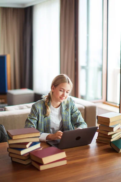 Aranyos tini lány diák alkalmi ruhákban ül a laptopnál könyvekkel. Vissza a suliba. Vizsgaelőkészítés — Stock Fotó