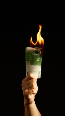 Siyah arka planda izole edilmiş Mans kolunda para yakmak. Protestolar, mali kriz ve iflasla ilgili konsept fotoğraf