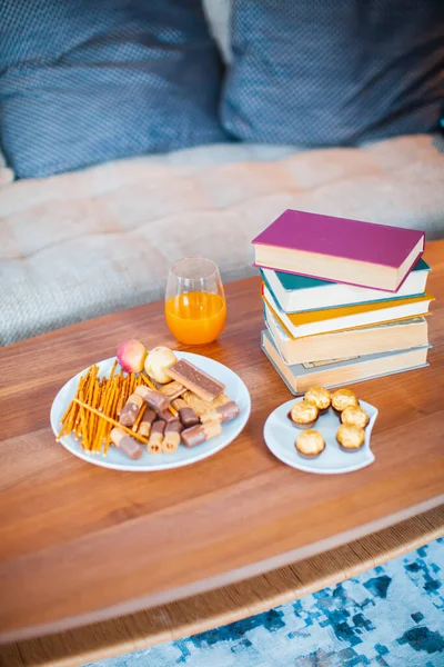 Κοντινό πλάνο χώρου εργασίας με βιβλία, γλυκά και ένα ποτήρι χυμό σε ένα δίσκο. Άνετο εσωτερικό σπίτι για αναψυχή — Φωτογραφία Αρχείου