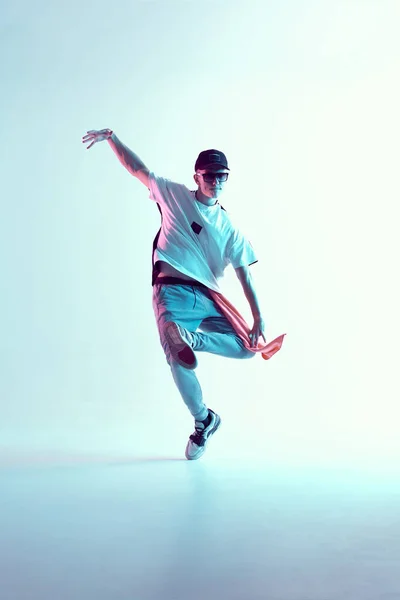 Ragazzo che balla nello studio di luci al neon. Ballerino acrobatico. Flessibile elegante. — Foto Stock