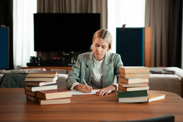 Drăguță școlăriță grijuliu care stă cu cărți la masă în clasă sau bibliotecă. Înapoi la școală — Fotografie, imagine de stoc