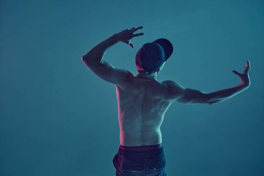 Neon mavi ışıkta hip-hop yapan break dansçı adam. Dans okulu posteri. Arkadan bak.