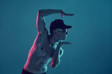 Genç break dansçı, neon mavi ışıkta üstsüz hip-hop yapıyor. Dans okulu posteri