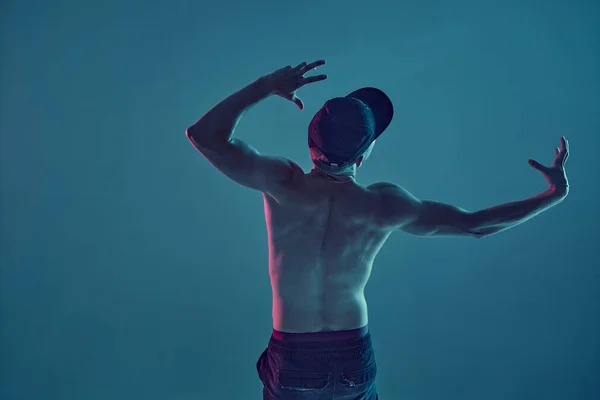 Хлопець розбиває танцювальну шапку хіп-хоп у неоновому блакитному світлі. Постер школи танців. Вид ззаду — стокове фото