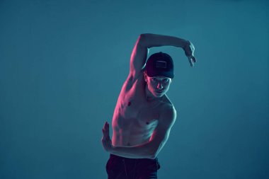 Şık genç bir break dansçı, neon mavi ışıkta üstsüz hip-hop yapıyor. Dans okulu posteri