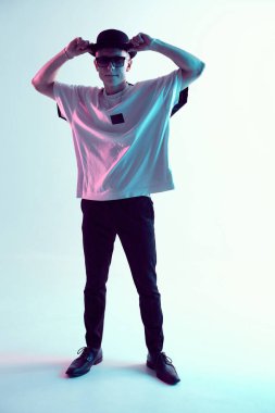 Şapkalı ve güneş gözlüklü genç break dansçı neon ışıkta duruyor. Dans okulu posteri. Savaş yarışması duyurusu