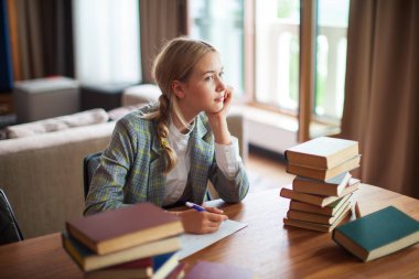Sınıfta ya da kütüphanede kitapları olan düşünceli genç kız öğrenci. Okula geri dön.
