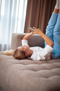 Akıllı telefonlu, boş ekran iletişimli, alışveriş yapan ya da kanepedeki rahat evinde dinlenen genç ve modern çağdaş bir kız.