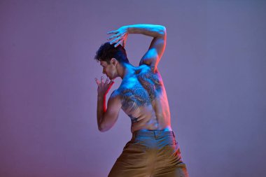 Neon ışıkta tişörtsüz havalı bir dansçı. Renkli dans okulu posteri. Dövmeli bir ceset. Arkadan görüntüle