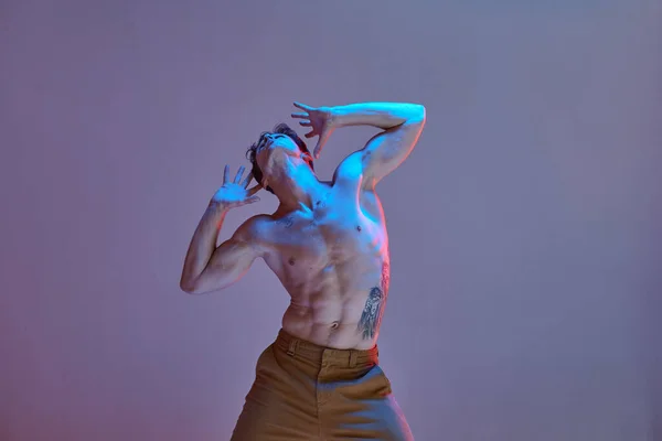 Cool jeune homme dansant danse expressive sans chemise dans la lumière au néon. Affiche d'école de danse. Corps avec tatouages. — Photo