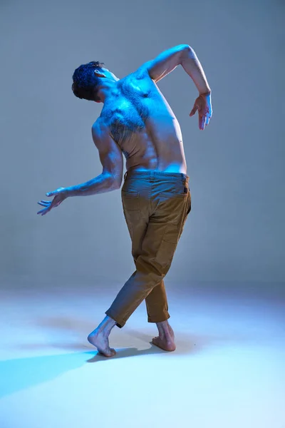 Fajny młody tancerz bez koszuli w neonowym świetle. Plakat szkoły tańca. Ciało z tatuażami. Widok z tyłu — Zdjęcie stockowe