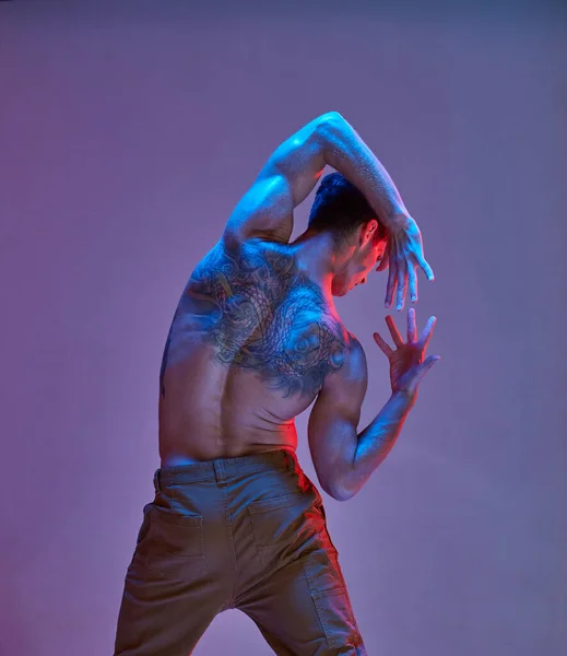 Ballerino figo senza camicia in luce al neon. Manifesto colorato della scuola di danza. Corpo con tatuaggi. Vista da dietro — Foto Stock