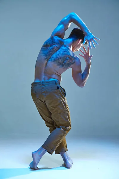 Fresco giovane ballerino senza camicia in luce al neon. Manifesto della scuola di danza. Corpo con tatuaggi. Vista da dietro — Foto Stock
