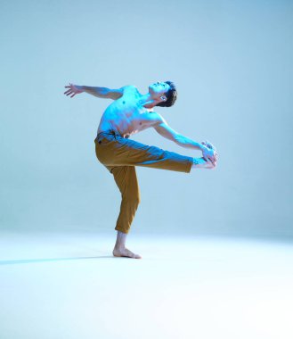 Neon mavi ışıkta tişörtsüz dans eden esnek, genç bir dansçı. Dans okulu posteri. Dans dersleri.