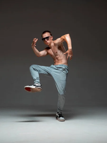 Un figo breakdancer con gli occhiali da sole che balla hip-hop senza camicia in studio. Manifesto della scuola di danza. Lezioni di break dance — Foto Stock