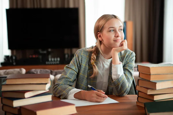 Fiatal aranyos mosolygós lány diák ül könyvek asztalnál osztályteremben vagy könyvtárban. Vissza az iskolába. — Stock Fotó