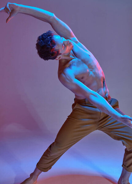 Cool young guy dancing expressive dance without shirt in neon light. Colorful dance school poster. Cropped photography