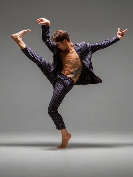 Cool young man dancer dancing expressive dance in suit in studio. Dance school poster. Dance lessons