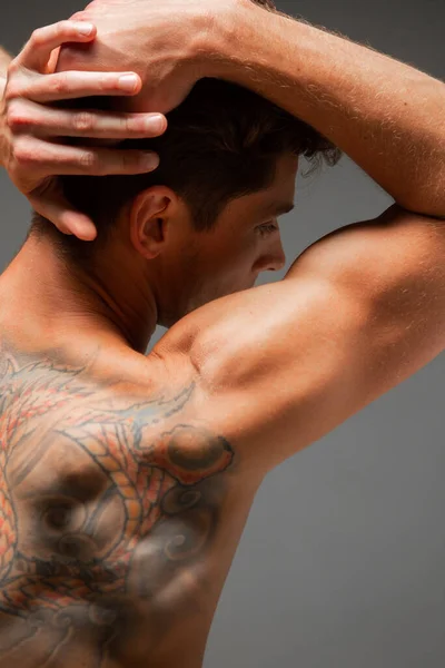 Portrait of handsome young guy with stylish haircut without shirt standing in studio. Body with tattoo. View from back — Stock Photo, Image