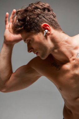 Kablosuz kulaklıklı şık genç adam tişörtsüz şarkı dinliyor. Müzik posteri