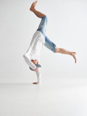 Genç break dansçı beyaz arka planda baş aşağı dans edip hip-hop yapıyor. Break dans okulu posteri