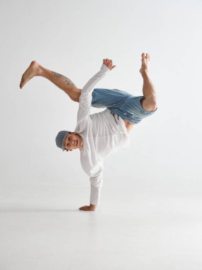 Genç break dansçı beyaz arka planda tek kollu hip-hop dansında duruyor. Break dans okulu posteri