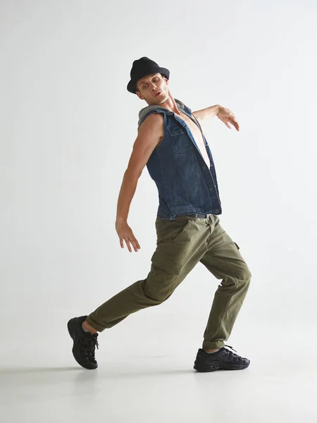 Fresco giovane breakdancer in cappello ballare hip-hop in studio isolato su sfondo bianco. Lezioni di break dance — Foto Stock