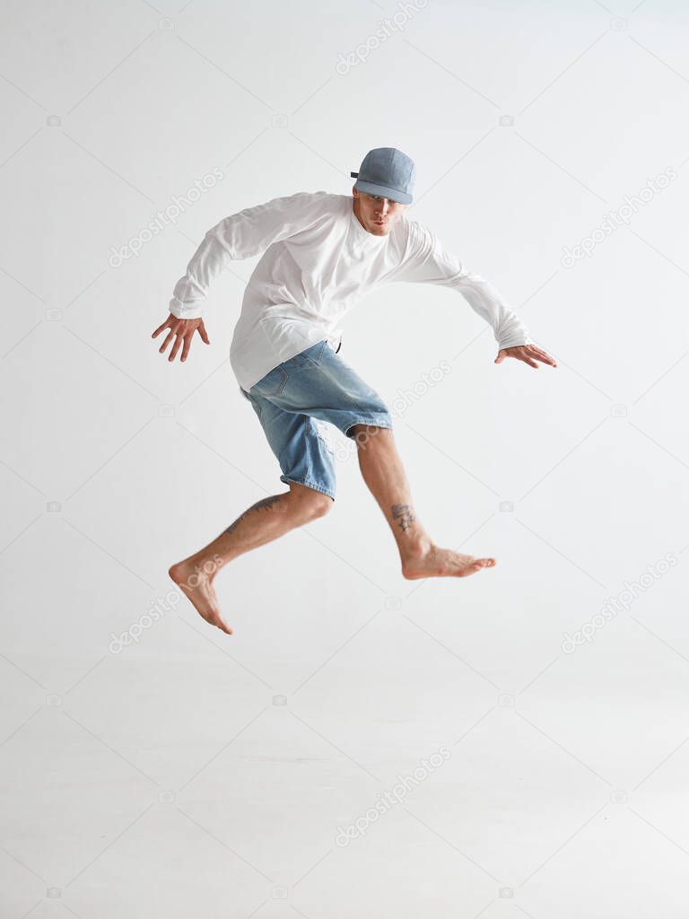 Cool young guy breakdancer jumps dancing hip-hop isolated on white background. Dance school poster. Break dance lessons