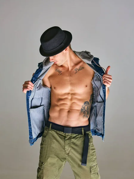 Cool hombre sexy breakdancer en sombrero de pie en el estudio aislado sobre fondo gris. Escuela de baile cartel —  Fotos de Stock