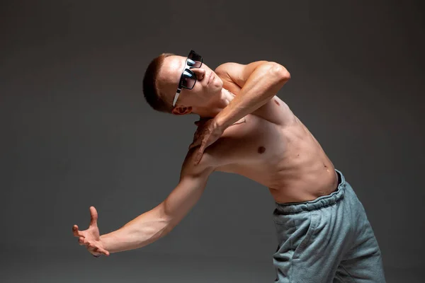 Jeune breakdancer fou en lunettes de soleil dansant hip-hop sans chemise en studio. Affiche école de danse — Photo