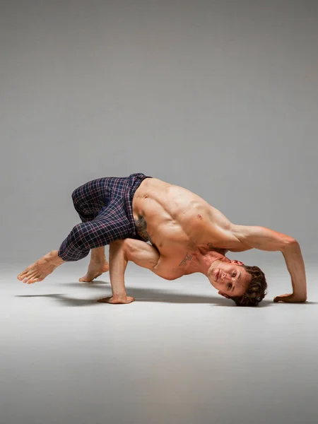 灵活的男子霹雳舞与赤身裸体的躯干跳舞较低的霹雳舞隔离在灰色的背景。中断舞蹈课 — 图库照片