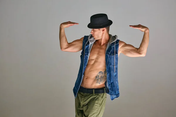 Jeune homme breakdancer dans la danse chapeau danse expressive en studio isolé sur fond gris. Corps avec tatouage — Photo