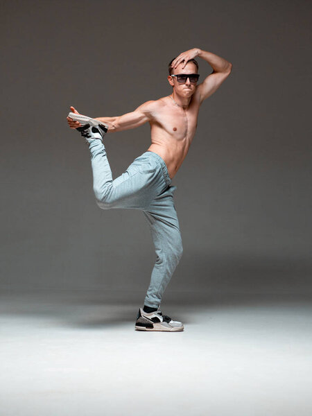 Крутой парень в солнечных очках танцует хип-хоп без рубашки в студии. Плакат танцевальной школы. Уроки брейка