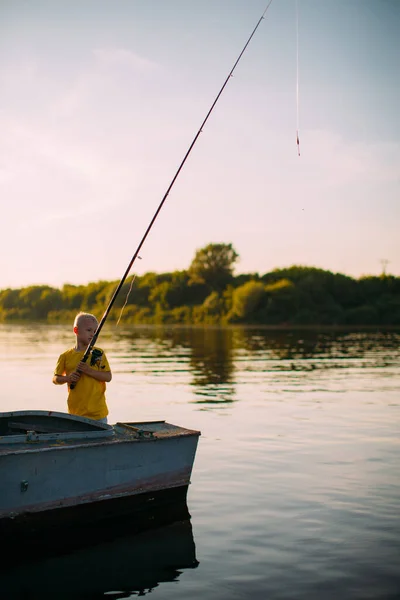 Bebé niño peces de pie con varilla en barco en el río en verano —  Fotos de Stock