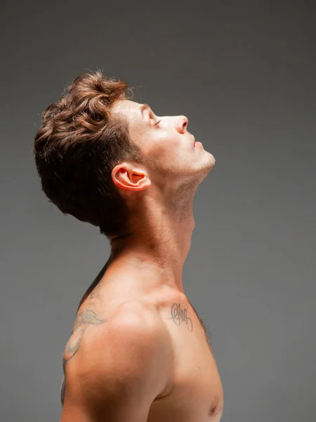 Portrait de beau jeune homme avec une coupe de cheveux élégante sans chemise debout en studio. Corps avec tatouage — Photo