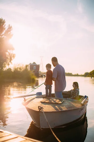 Young family fishing on boat in summertime. Father teaches son fishing. Back view. Photo for blog about family travel — Stock Photo, Image