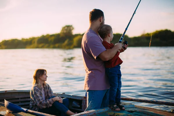 Joven pesca familiar en barco en el río en verano. Padre enseña a pescar. Foto para blog sobre viajes en familia —  Fotos de Stock